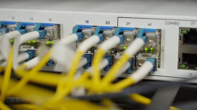 Optical server and router of the data center server room. Network equipment blinking with lights on rack. Optical fiber wires connected to ports. High speed internet.