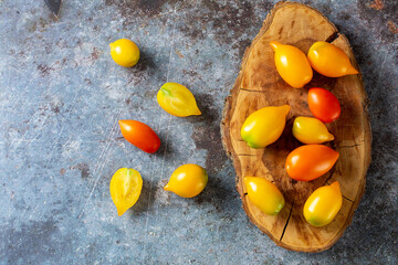 various colorful ripe tomato on rustic blue background. Cooking from yellow orange and red cherry tomatoes.