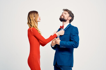 a man in a suit next to a woman in a red dress emotions hand gestures light background