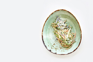 Asian wakame salad. Bowl on kitchen table. Modern dishes. Carrot, cucumber and mayonnaise dinner. Chuka herbs