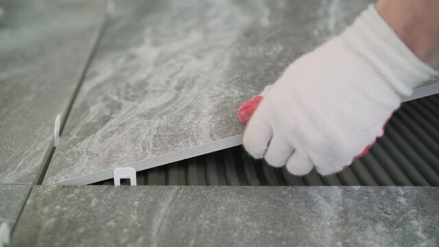Installing a large ceramic tile. Worker laying floor tiles. Laying large ceramic tiles on the floor.