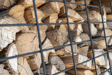 Firewood behind an iron black grate. Place of storage of firewood