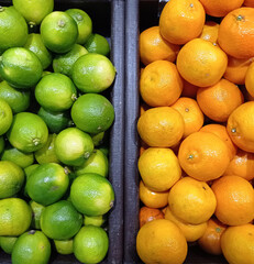 Many juicy bright limes and oranges on a market counter. Close-up. Background.