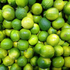 Many juicy bright limes on a market counter. Close-up. Background.