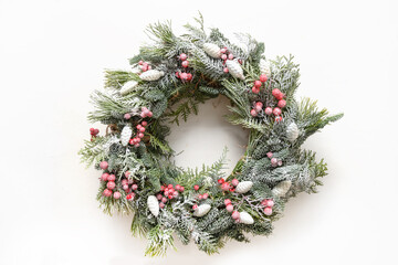 Fototapeta na wymiar Christmas wreath of fresh natural evergreen branches with red and white decorations in center of white background. New Year greeting card. Top view. Traditional decoration for Xmas holiday.