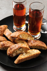 Tasty cantucci and glasses of liqueur on grey table, closeup. Traditional Italian almond biscuits