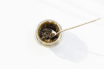 Caviar black in glass jar on a silver  spoon, selective focus