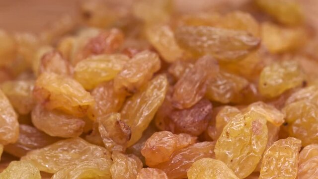 Close-up of yellow dried raisins. Dried raisins rotate on a wooden platform