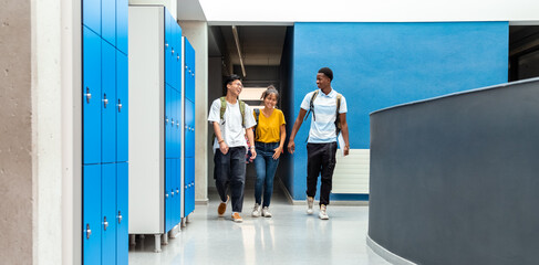Group of teen high school students laughing walking in school corridor. Horizontal banner image. Copy space.