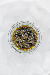 Premium caviar black in glass jar served in ice cube, selective focus