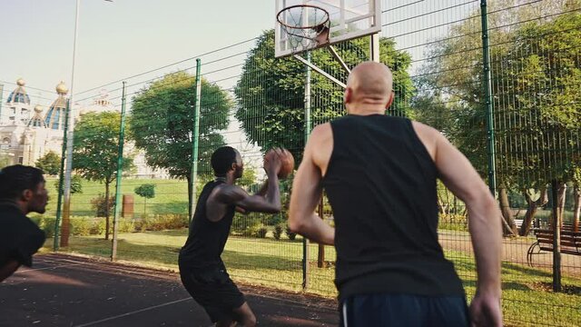 Friendly match on the basketball field, multiracial group of athletes. Basketball team practice at sunrise