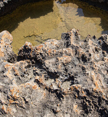backgrounds and texture on the seashore in stone deposits flooded with water and the remains of sea salt frozen in time
