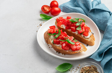 Bruschetta with tomatoes, feta and basil on a gray background.