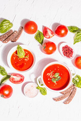 Bowls with homemade tomato soup. Ripe vegetables, fresh basil leaves, breadsticks, aromatic spices