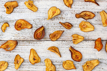 A pile of dried pears in slices on a white wooden background. Dried fruit chips. Healthy food
