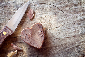 Carved wooden heart and knife on old wooden background. Romantic love concept