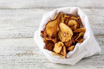 A pile of dried slices of pears in white pouch on wooden background. Dried fruit chips. Healthy food