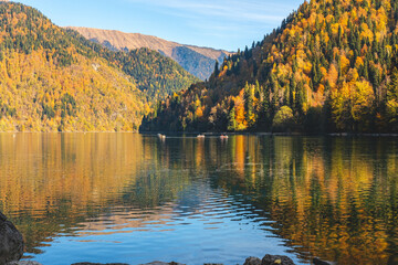 Beautiful view on the mountain lake with the colorful autumn trees on the hills.