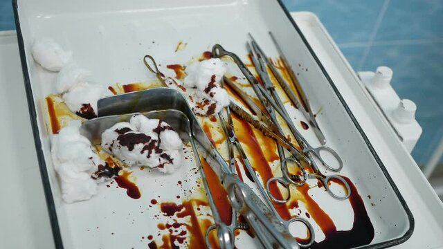 Dirty bloodstained medical utensils and tools on a gloomy table