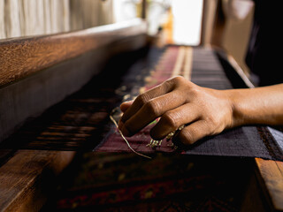 old woman hand weaving using traditional weaving instrument