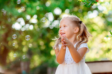 little girl catches soap bubbles in the park