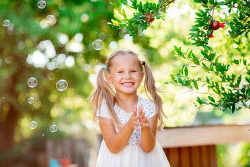 little girl catches soap bubbles in the park