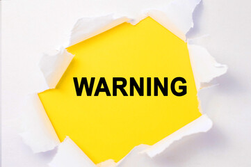 The word warning is written on a yellow background that is in the center of a white torn sheet.