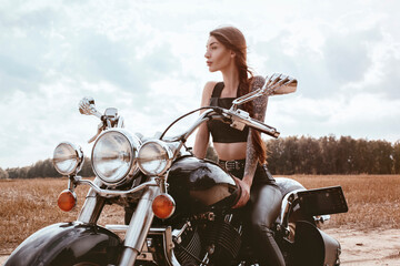 Young sexy girl posing on a motorcycle at sunset. Motor sport concept.