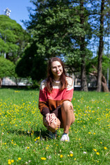 A beautiful young lady sitting on the grass enjoying life, feeling happy and relaxed in the park