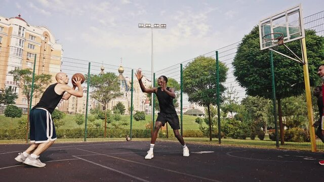 Three-point shot. A young basketball player throws the ball into the basket, his opponent tries to prevent him. Successful throw finish