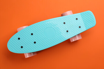 Turquoise skateboard on orange background, top view