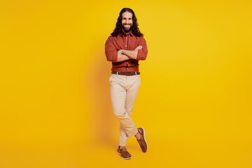 Portrait of cheerful business man guy crossed hands posing on yellow background