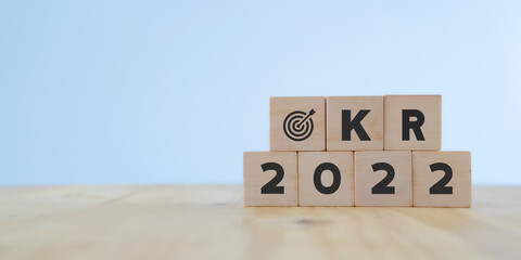 OKRs : Objective key result in 2022 concept. Word OKR , year 2022  and target icon on wooden cubes...