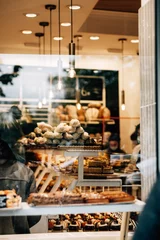 Tuinposter Verticaal schot van buiten een bakkerij vol klanten met smakelijke desserts en broodjes © Tomáš Hustoles/Wirestock