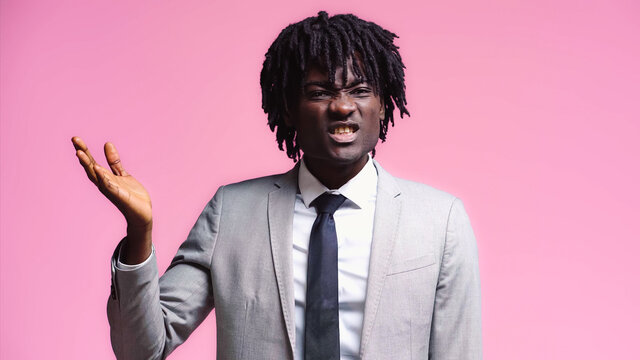 Skeptical african american businessman pointing with hand isolated on pink
