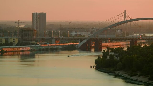 Panoramic view of Kyiv city, industrial buildings and constructions, river and its coasts, evening landscape. Motor boat moves down the river under the bridge. Tranquill background