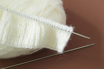soft white wool yarn and knitting needles