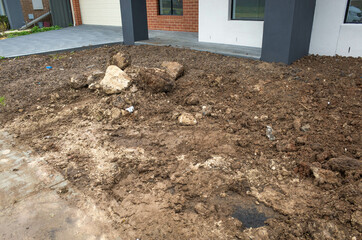 Piles of dirt at a front yard garden of a new residential house. An incomplete landscaping project on a construction site. Melbourne, VIC Australia.