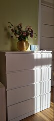 white chest of drawers with a vase of flowers