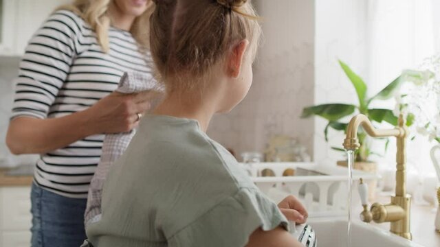 Close up video of girl helps mother to wash dishes. Shot with RED helium camera in 8K