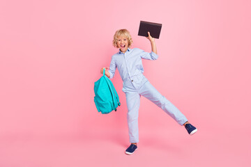 Photo of pretty lucky school boy wear blue shirt backpack smiling holding book walking isolated...
