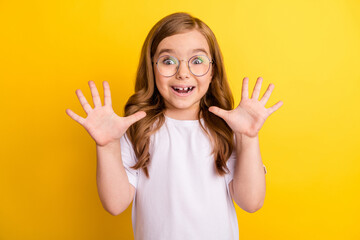 Photo of little impressed blond girl arms up wear spectacles white t-shirt isolated on yellow color background