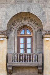 Fototapeta na wymiar a window with an arch and a balcony in a stone house