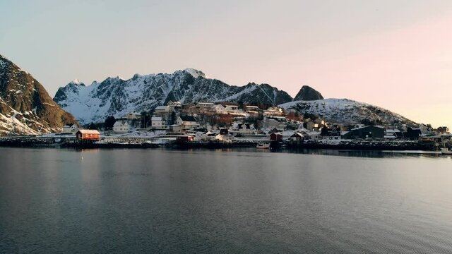 Flying to scandinavian village in valley on arctic coastline at evening. Lofoten islands, Norway