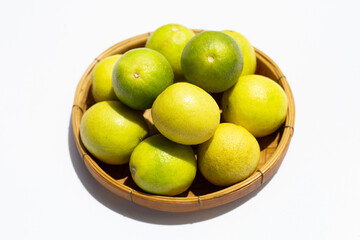 Limes in bamboo basket on white