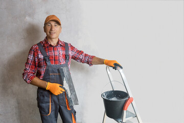 A plasterer, a builder with  spreading trowel in front of wall. Concept of home renovating by individual people.