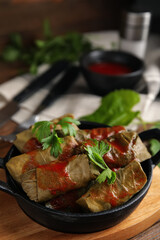Delicious stuffed grape leaves with tomato sauce on wooden board