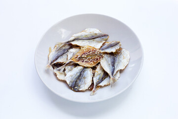 Dried fish with sesame seeds in white plate on white background.