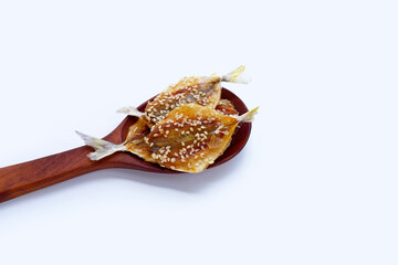 Dried fish with sesame seeds on white background.