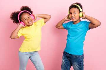 Portrait of two attractive cheerful friends friendship listening pop having fun isolated over pink color background